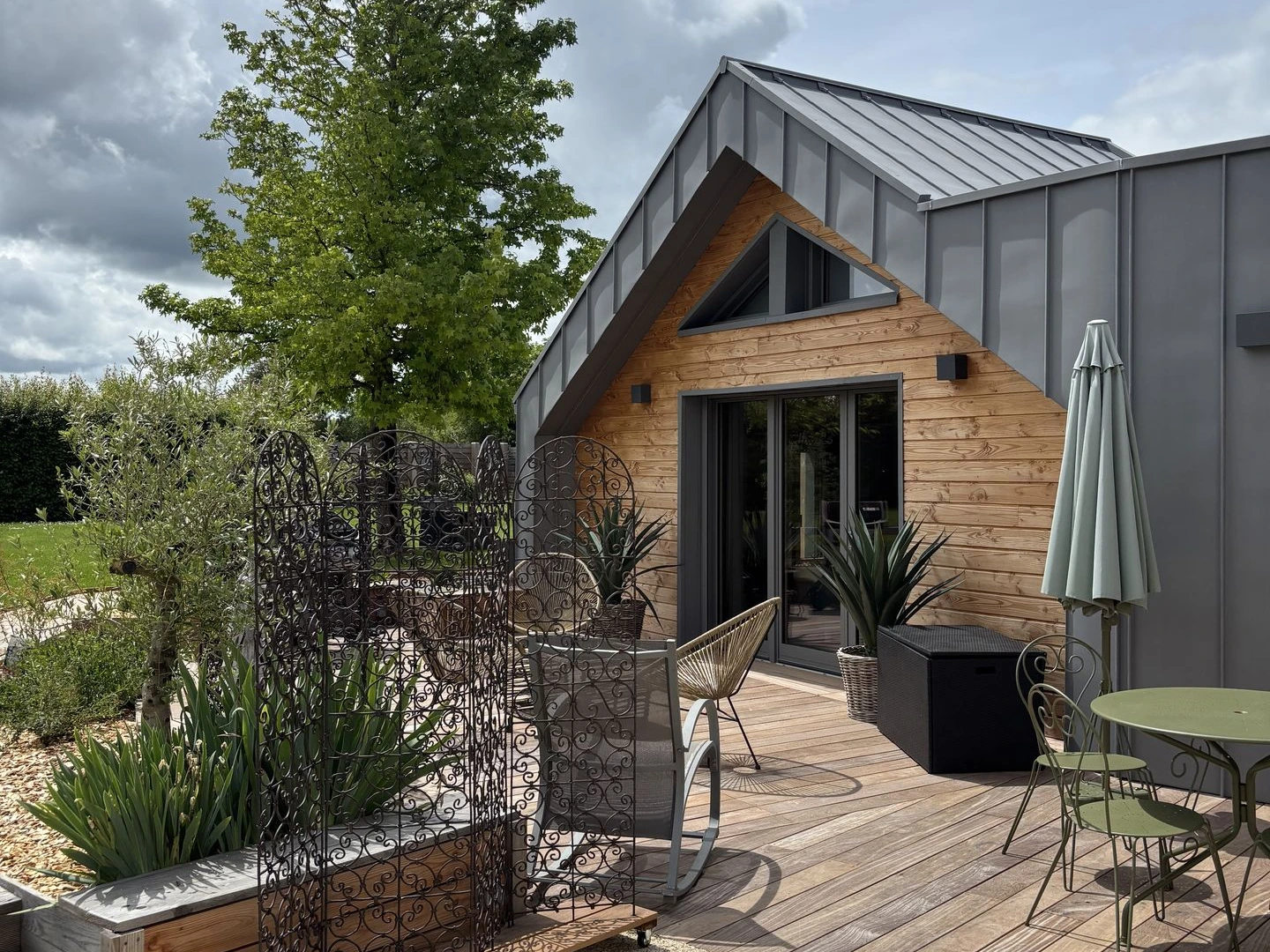 Une grande baie vitrée s’ouvre sur la terrasse attenante, offrant une vue agréable sur le jardin paysager de la propriété. Équipée d’un salon de jardin, c’est l’endroit idéal pour profiter du calme et des beaux jours.